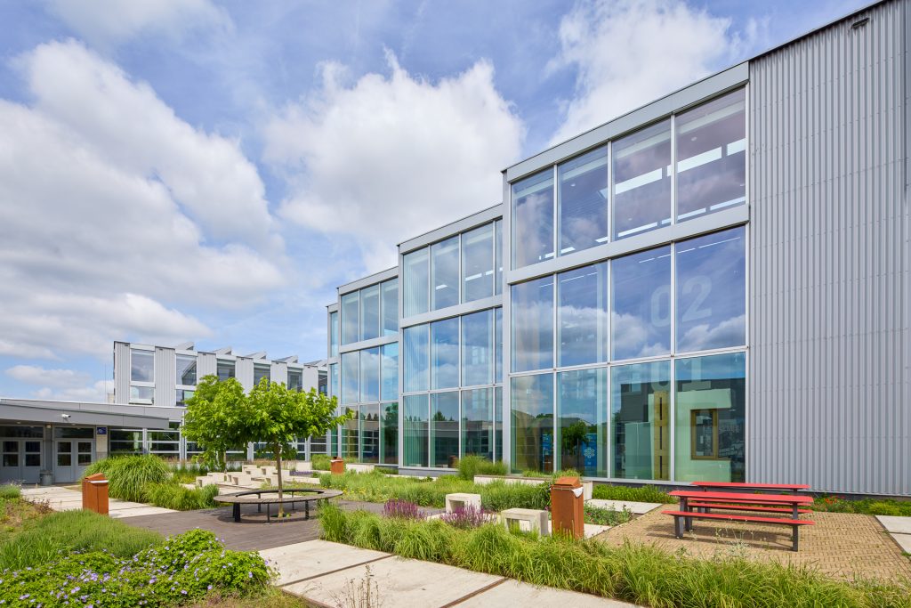 Binnenplein met zonwerend glas, groen en zitplekken bij Koning Willem I College