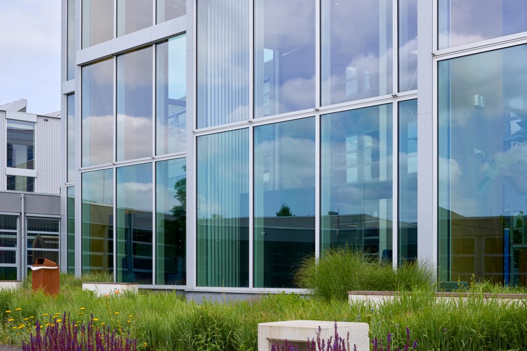 Modern gebouw met zonwerend glas en groene beplanting bij Koning Willem I College