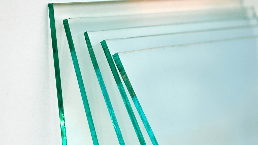 Zes transparante platen van floatglas met een groene rand, zorgvuldig gestapeld tegen een witte achtergrond.