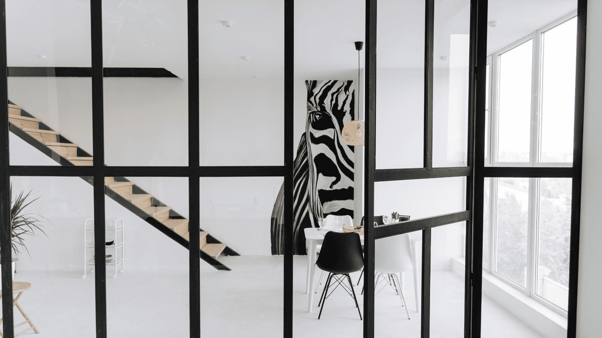 Moderne woonkamer met gelaagd glas (letselveiligheid), zwart-wit interieur en opvallend kunstwerk.