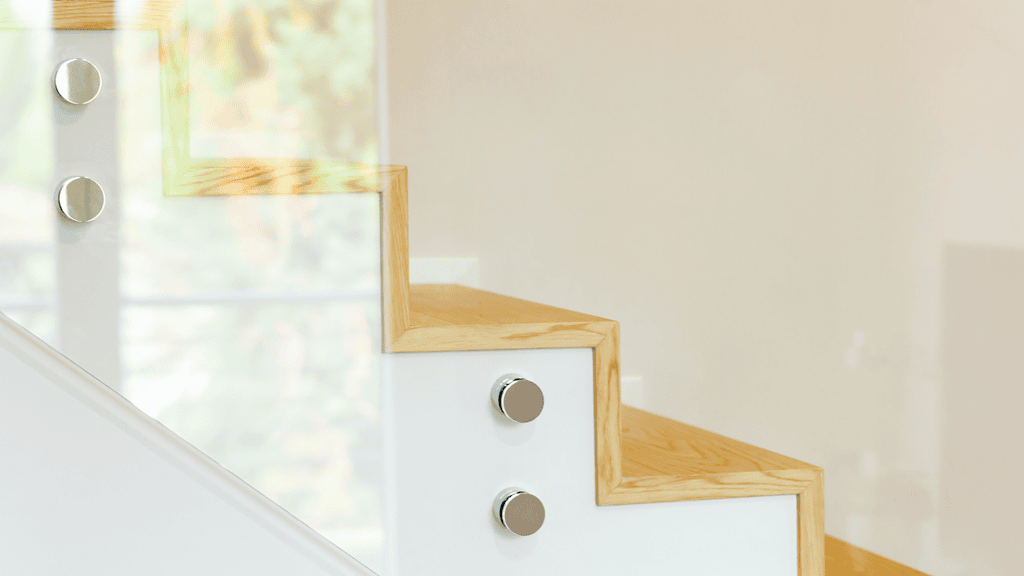 Een moderne trap met leuning van gehard glas met traptreden van licht hout. 